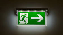 Illuminated green emergency exit sign showing the direction to the nearest exit